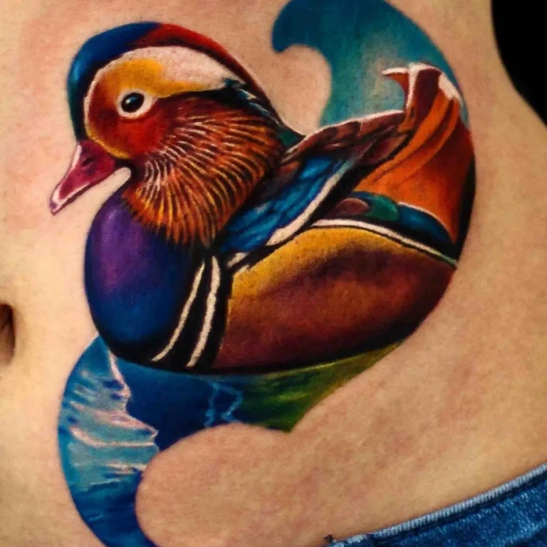 Ein Tattoo im Color Tattoo Style, das eine farbenfrohe Mandarinente mit lebhaften Blau-, Gelb- und Orangetönen darstellt.