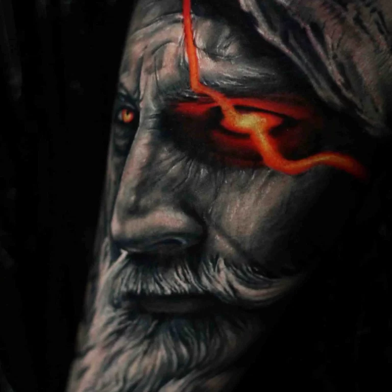 Ein Tattoo im Color Tattoo Style, das das Gesicht eines Mannes mit einem glühend roten Auge und realistischer Schattierung darstellt.