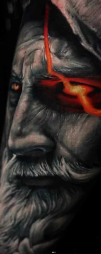 Ein Tattoo im Color Tattoo Style, das das Gesicht eines Mannes mit einem glühend roten Auge und realistischer Schattierung darstellt.