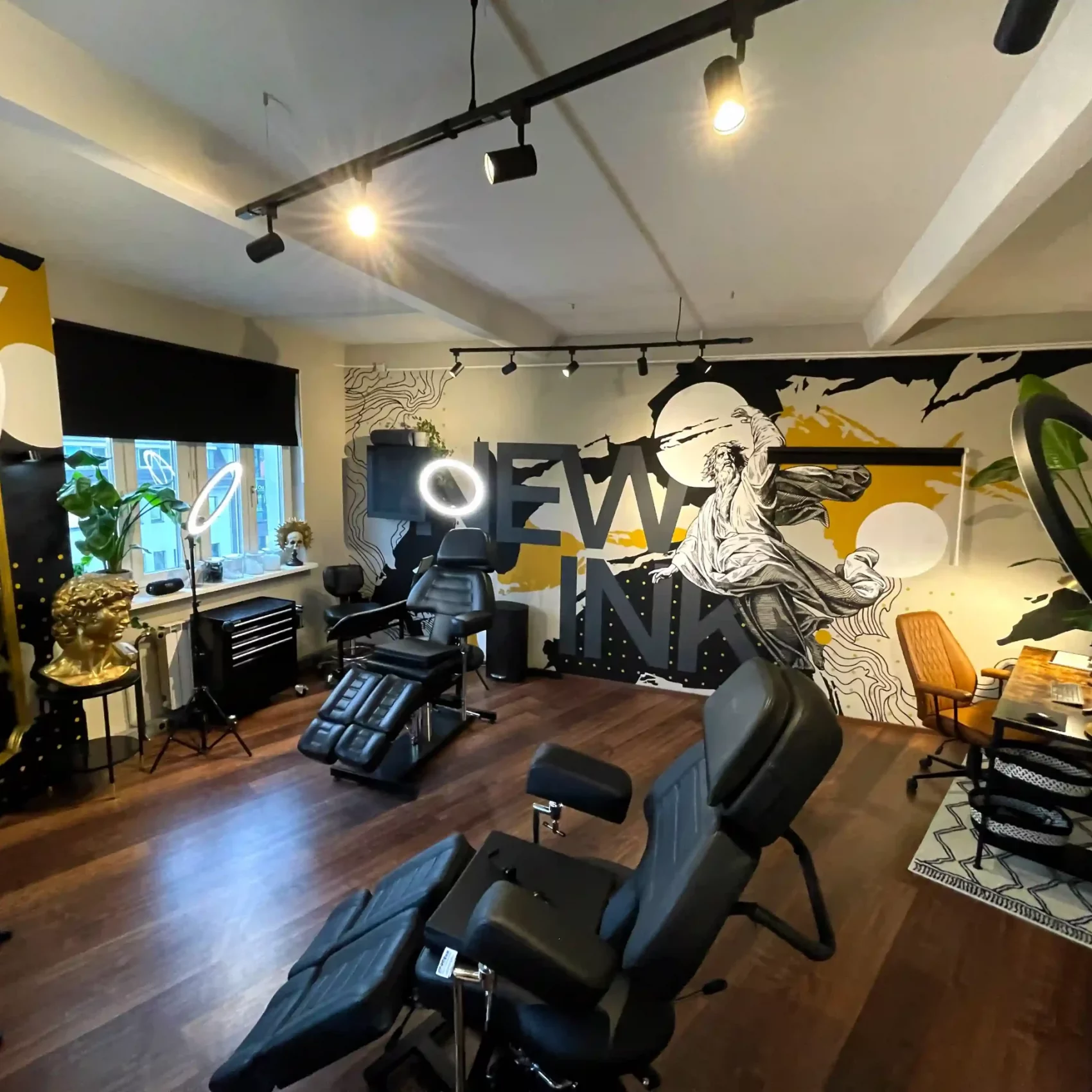 Ein moderner Tattoo-Raum im Nextink Tattoo Studio Berlin mit bequemen Tätowier-Stühlen, goldenen Dekorationen und einer auffälligen Wandkunst.