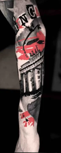 Ein Unterarm-Tattoo im Trash Polka Tattoo Style, das das Brandenburger Tor mit abstrakten roten und schwarzen grafischen Akzenten darstellt.