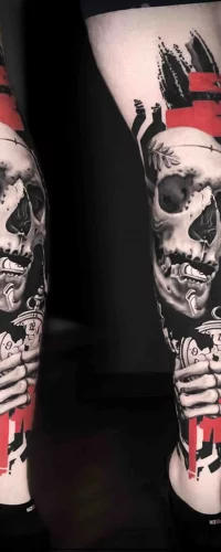 Ein Bein-Tattoo im Trash Polka Tattoo Style, das einen Totenkopf mit einer Taschenuhr und kräftigen roten und schwarzen grafischen Elementen kombiniert.
